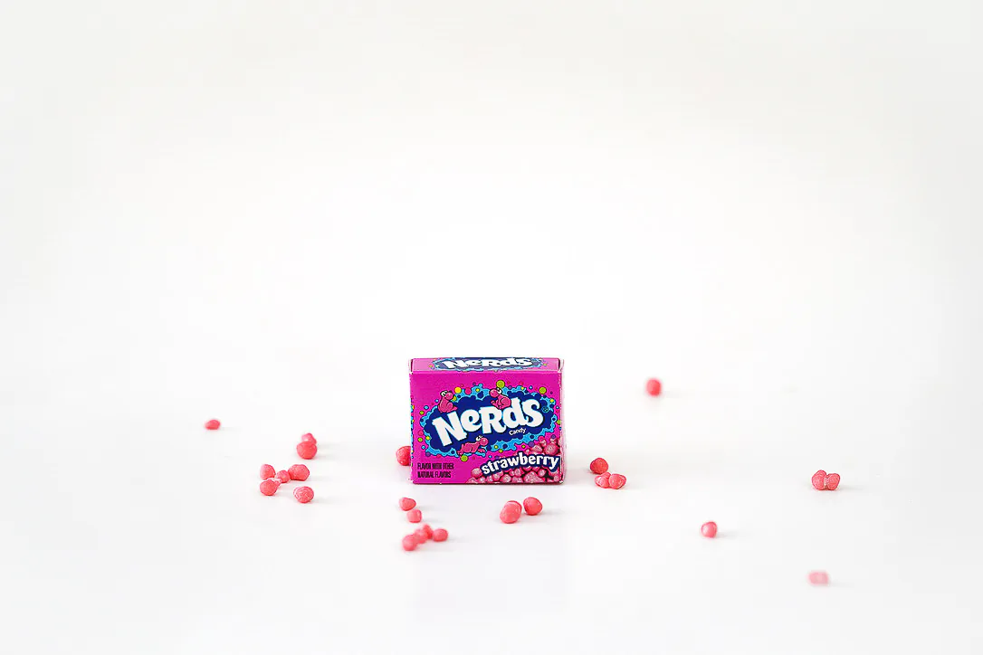 A pink box of strawberry candy arranged with pieces on white