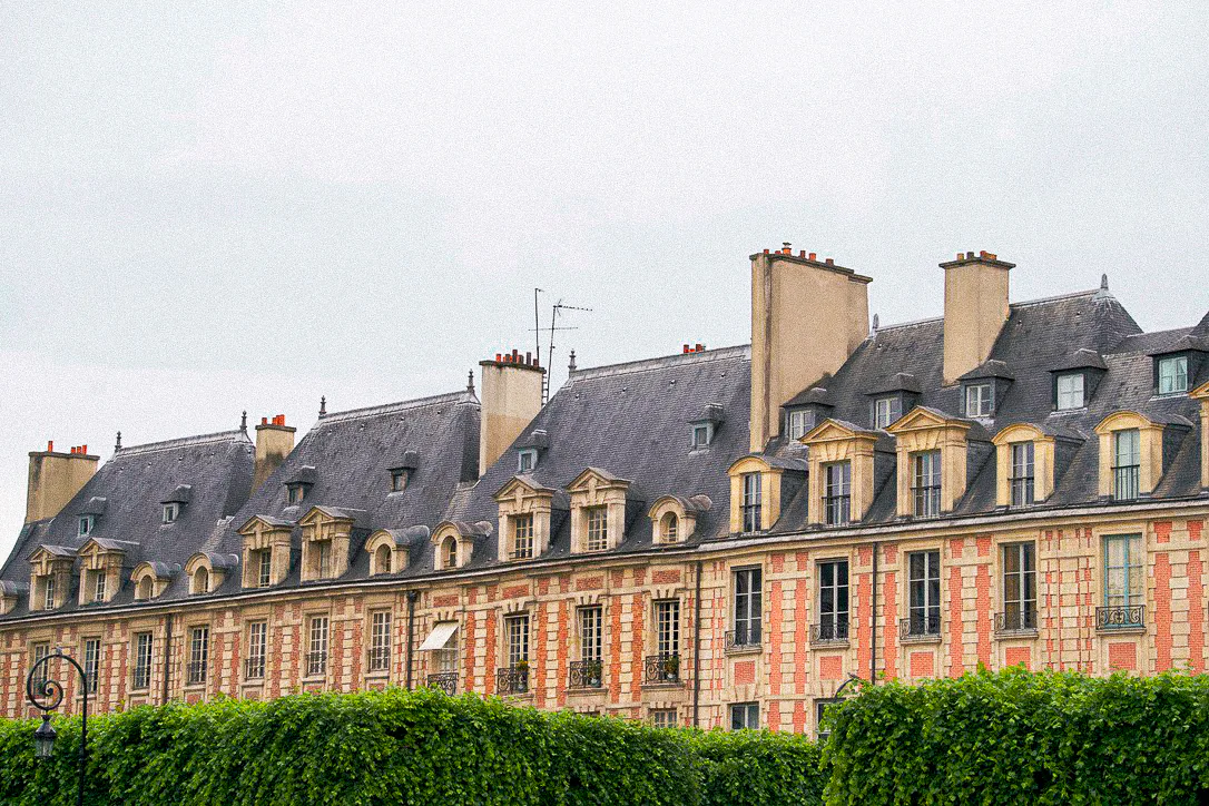 Historic red brick and stone buildings beneath a pale Paris sky