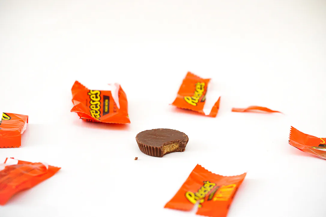 Reese's candy and wrappers arranged on a white studio surface