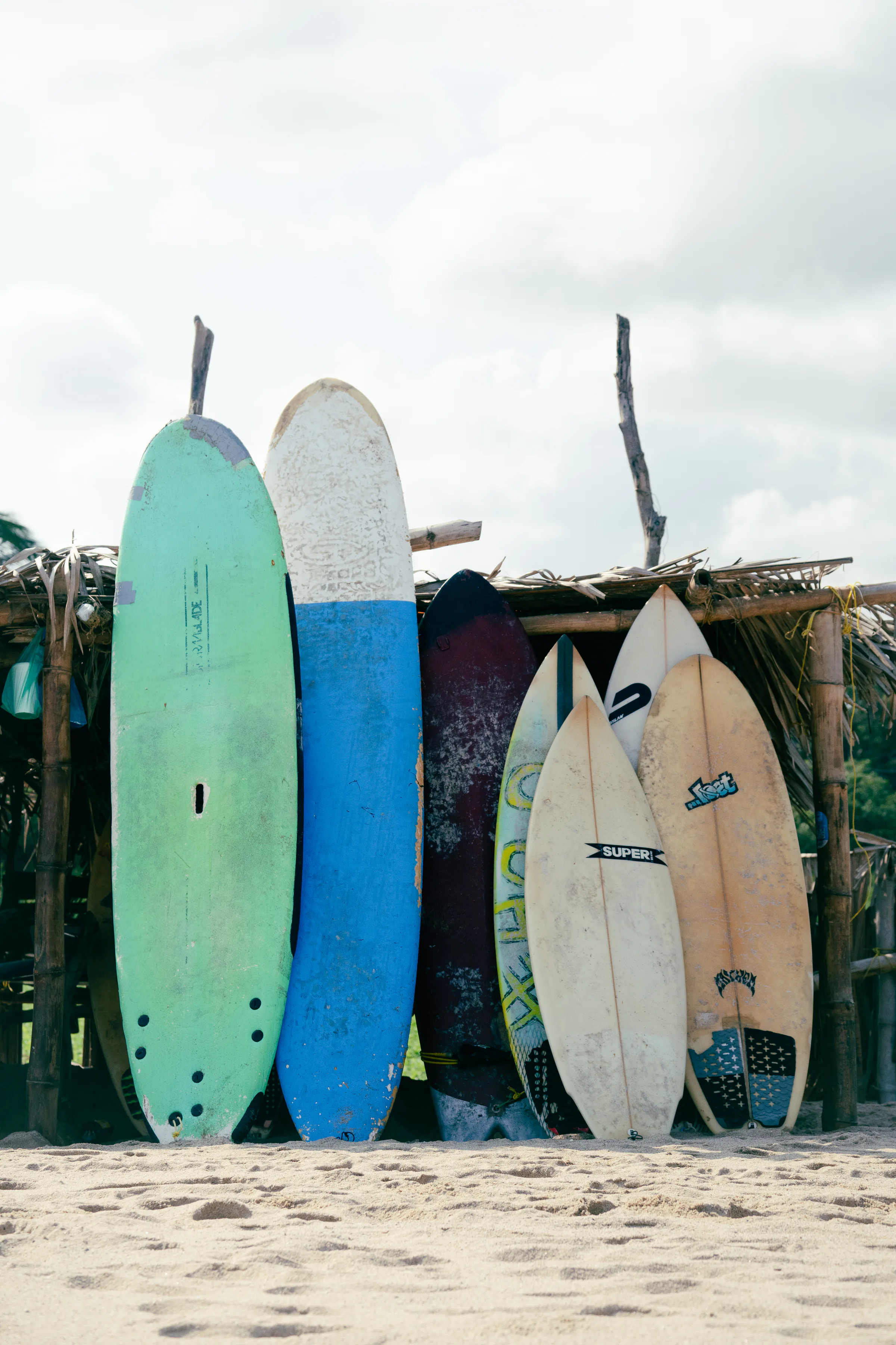 A colorful collection of surfboards standing in the sand